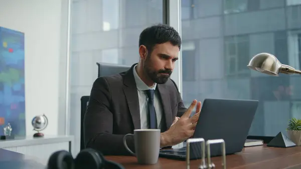 Serious businessman solving issues working on modern laptop at workplace close up. Skilled company employee typing computer focused on monitor. Bearded businessman busy of remote job in luxury office.