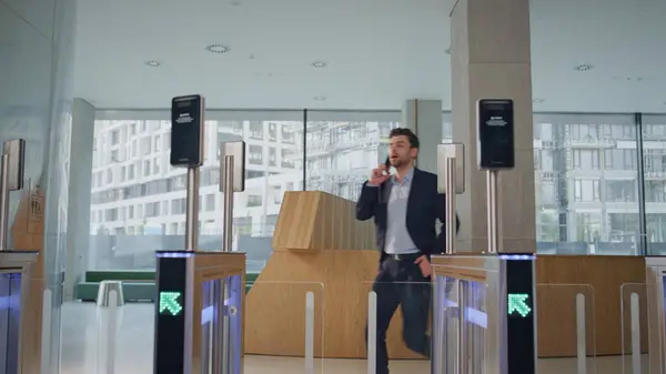 Business man open turnstile waving to face id screen at modern business center. Calling businessman hurrying through automatic gates office hall. Worried manager running on workplace. Security system