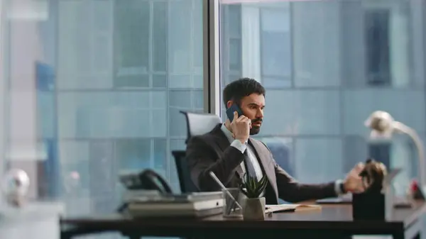 Furious businessman finish call angry about displeased conversation sitting office desk. Exhausted bearded company employee hung up telephone feeling stressed. Frustrated man manager worried crisis.