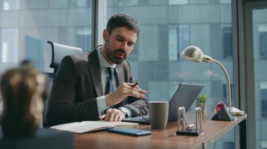 Şirket çalışanı Webinar 'ın ofis masasında oturup notlar aldığını söylüyor. Müdür online toplantıda dizüstü bilgisayar kamerasına bakarak konuşuyor. Sakallı iş adamı video görüşmesinde işi tartışıyor.