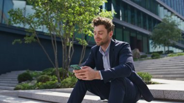 Akıllı telefondan mesaj yazan yakışıklı yönetici merdivenlerden zoom yaparak uzaklaşıyor. Gülümseyen işadamı, Sunny Caddesi 'nde cep telefonuyla mesajlaşıyor. Ofis dışında cep telefonuyla rahatlayan zarif bir işçi..