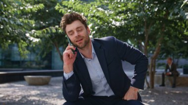 Kendine güvenen girişimci cep telefonuyla konuşuyor. Sunny Square 'de oturuyor. Gülümseyen iş adamı dışarıdaki cep telefonuyla ortakları arıyor. Başarılı yönetici parkta telefon ile dinlenme ile istemciye danışıyor.