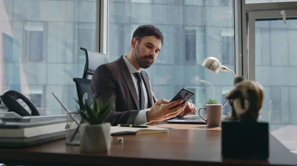 Businessman start work call sitting office table with laptop. Confident bearded executive manager talking at smartphone discussing business project. Elegant successful director giving tasks by phone.