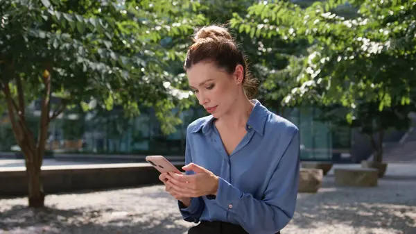 Rolig Forretningskvinne Skriver Melding Smarttelefonen Sitter Solfylt Grønn Park Nært – stockfoto