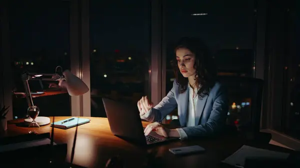 Unmotivated woman manager typing laptop feeling sleepy at workplace. Overworked businesswoman working at computer sitting office desk late evening. Tired company employee overwhelmed by overtime job.