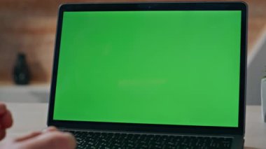 Kimliği belirsiz bir adam sabah iş yerinde klavye yeşil ekran dizüstü bilgisayarı kullanıyor. Ofisteki kromakey bilgisayarı kullanarak uzaktan çalışan genç bir serbest çalışan. İnternetten e-posta gönderen adam 