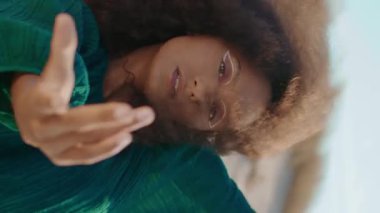 Kum tepeleri üzerinde doğaçlama dans eden esnek Afrikalı Amerikalı kadın. Kıvırcık genç esmer dansçı vücudunu baştan çıkarıcı bir şekilde eğiyor. Çölde siyah elbiseler giyen kıvırcık kız