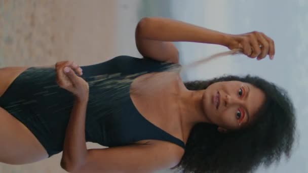 非洲裔美国女孩模型走在沙滩上倒沙子在手中夏季黄昏垂直特写 一个身穿黑色泳衣的沉着的梦幻女子独自在海滨享受漆黑的夜晚 — 图库视频影像