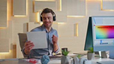 Mutlu yönetici kablosuz kulaklıkla müzik dinliyor. İş yerindeki gazetelere bakıyor. Bilgisayarda çalışan, kulaklıklı, ritmik seste dans eden gülümseyen bir iş adamı. Neşeli tasarımcı iş akışı.