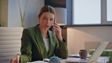 Sinirli tasarımcı, akşam ofiste cep telefonuyla konuşuyor. Stresli kadın elinde kağıtlarla üzgün yüzüyle yükseltilmiş tonlarda konuşuyor. Kızgın resmi proje yöneticisi dizüstü bilgisayarda çalışıyor 