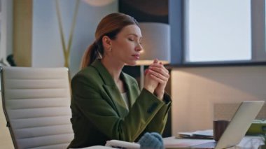 Yorgun yönetici dizüstü bilgisayar ekranına bakıyor. Hafif iş yerinde kahve fincanı çekiyor. Modern ofis içinde çalışan ciddi bir kadın. Sakin zengin iş kadını bilgisayar masasında tek başına oturuyor. 