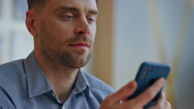 Yakın plan adam ışık odasında akıllı telefon kullanıyor. Ofiste mutlu iş danışmanı kayan cep telefonu. Kapalı alanda cep telefonu ekranı gören pozitif gülümseyen işçi. Başarılı iş adamı çevrimiçi okuma