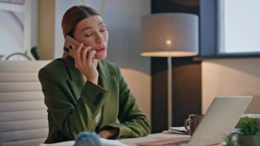 Akşam kapanış konuşmasında telefonla konuşan mutlu işçi. Gülümseyen pozitif iş kadını telefon görüşmesinde şikayet ediyor yaratıcı ajansta laptopta çalışıyor. Neşeli kız tek başına akıllı telefondan konuşuyor. 