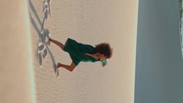 非裔美国女演员躺在沙丘上跳舞 夏风吹拂着垂直的天使 动情的塑料女舞蹈演员在沙漠中表演色情动作 卷曲的黑发衣衫褴褛 — 图库视频影像