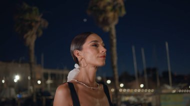 Romantik bir buluşmada sokağa çıkan güzel bir bayan. Kapatın. Gülümseyen kaygısız kadın gece kentinde rahat hafta sonunun tadını çıkarıyor. Hayalci genç kız gülümseyerek karanlık şehir caddesinde geziniyor..