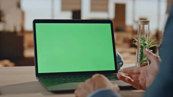 Closeup businessman having videocall at green screen computer in office. Unrecognizable boss using mockup digital device zoom on. Male person gesturing hands to chroma key laptop screen at work desk