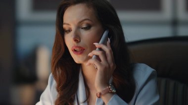 Kapalı gişe, akşam ofisinden gelen çağrıya cevap veriyor. Deri koltukta cep telefonuyla konuşan pozitif bir kadın. Lüks karanlık şirket işyerinde müşteriyle sohbet eden dostane bir iş kadını. 