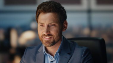 Akşam ofisinde çalışan gülümseyen adam. Başarılı yönetici gece geç saatlerde mali iş stratejisi üzerinde çok çalışıyor. Panoramik pencere dolabında iyi haber e-postalarını okuyan mutlu işadamı 