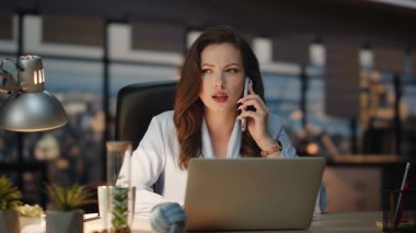 Kendine güvenen patron, şehir merkezindeki cep telefonunu arıyor. Odaklanmış bir kadın panoramik pencere dolabında akıllı telefonlardan konuşuyor. Pozitif iş kadını gece geç saate kadar çalışıyor.