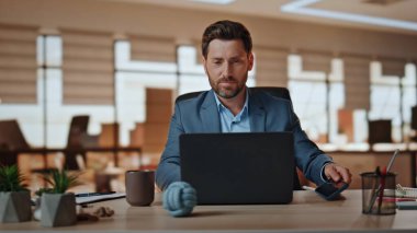 Olumlu patron modern ajansta çalışan cep telefonunu bırakıyor. Gülümseyen yakışıklı iş adamı dizüstü bilgisayar ekranı sakin atmosferde sunum hazırlıyor. Sakallı yönetici bilgisayar masasında oturuyor.