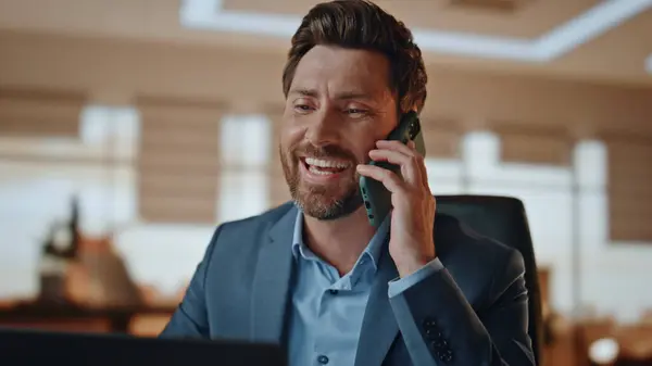 Happy manager make call in office closeup. Smiling freelancer get job promotion reacting at great news at modern beige cabinet. Cheerful business man calling mobile phone talking with toothy smile