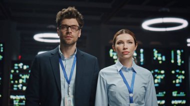 Gülümseyen meslektaşlar veri merkezine yakın çekim yapıyor. Teknoloji ofis fotoğraflarına bakan başarılı, mutlu yazılım mühendisleri. Pozitif kadın karanlık odada takım arkadaşıyla kollarını kavuşturdu.