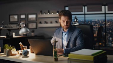 Düşünceli adam gece kabinesinde akıllı telefon ihbarını kontrol ediyor. Odaklanmış patron panoramik karanlık ofiste cep telefonu haberleri okuyor. Akıllı yönetmen bilgisayar işyerinde cep telefonu ekranı arıyor