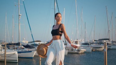 Hayalperest kadın elinde hasır şapkayla iskelede dinleniyor. Lüks beyaz yatlarda şık giyinmiş zarif bir kadın. Kaygısız gülümseyen kız okyanus kıyısında tek başına duruyor..