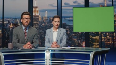 Two presenters broadcasting news at mockup television media channel closeup. Happy anchors hosting newscast standing chromakey tv studio. Charismatic couple newscasters talking collaborating in air clipart
