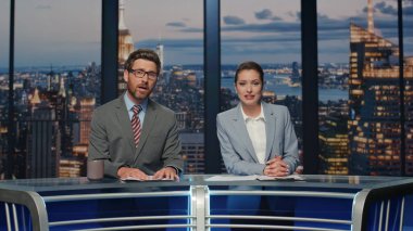 Presenters broadcasting breaking news at late studio closeup. Friendly couple professional newscasters working on tv studio stage talking to viewers. Elegant smiling hosts speaking at evening newscast clipart