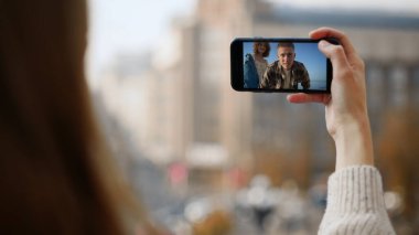 Yolculukta akıllı telefon sallayan mutlu arkadaşlar. Şehir caddesinde yakın plan kadın cep telefonu. Neşeli, gülümseyen bir çift cep telefonu ekranında görüntülü konuşma yapıyor. Uzak aile arıyor. Haberleri paylaşıyorlar.