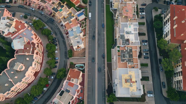 Aerial view cozy town district with red rooftops buildings green parks. Asphalt road running by residential houses to waterfront. Beautiful touristic coastal city drone shot. Mediterranean cityscape.