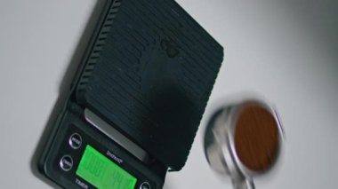 Bilinmeyen barista, portafinter 'de kahvesini elektronik ölçekte ölçüyor. Adamın eli robusta arabica ile dikey espresso yapmak için tartılıyor. Lezzetli bir içki hazırlıyorum. 