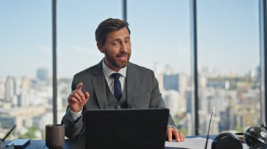 İş koçu modern ofisten görüntülü konuşmayı arıyor. Neşeli iş adamı ortağıyla sanal görüşme yapıyor. Gülümseyen orta yaşlı yönetici panoramik iş yerinde online konuşma dizüstü bilgisayarına danışmanlık yapıyor.