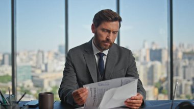 Cam ofiste işletme müdürü çalışma raporu. Sakallı adam şehir manzarasında çalışan şirket gazetelerini okuyor. Masadaki kameraya bakan yakışıklı bir şirket çalışanı. Orta yaşlı girişimci konsepti