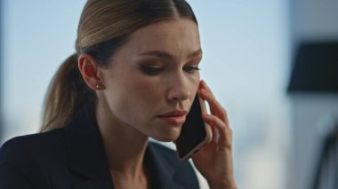 Ofiste çalışan ciddi bir işçi hücresi. Yakın çekim. Profesyonel bayan yönetici danışman müşteriyle konuşuyor. Güzel genç iş kadını cep telefonuyla mali sorunları tartışıyor..