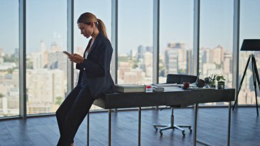 Kurumsal patron, çağdaş panoramik ofiste dinlenen akıllı telefondan mesaj atıyor. Gülümseyen, rahat bir kadın masa başında oturmuş iş yerinde cep telefonu kullanarak sohbet ediyor. Sosyal medyayı kontrol eden sakin işçi.