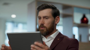 Ofiste tablet tutan üzgün adam. Endişeli iş adamı iş yerinde kötü haberler okuyor. Patron koltukta oturduğu için üzgün. İş sorunundan dolayı CEO şoku 