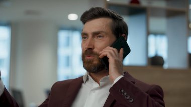 Ofiste başarılı bir iş adamı telefonla konuşuyor. Zarif lider iş ortağına detayları açıklıyor. Akıllı telefon konuşması yapan pozitif işçi. Şirket yaşam tarzı kavramı 