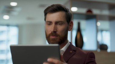 Ofiste tablet kullanan mutlu bir işadamı. Dijital cihazda gülümseyen yönetici sohbet mesajı. İnternette gezinen pozitif yönetmenin kırılması. Heyecanlı patron sosyal ağda iletişim kuruyor.