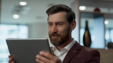 Ofisteki sakallı çalışan videosu yakın çekimde. Neşeli şef dinlenme odasında ped kullanıyor. Elinde dijital tablet olan yakışıklı bir iş adamı arkadaşıyla internette konuşuyor. Müşteriyle gülümseyen CEO sohbeti 