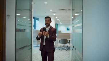 Yürüme koridorunu kapatırken çekilen mutlu çalışanlar videoları. Akıllı iş adamı cep telefonuyla selamlama elini tutuyor. Kendine güvenen proje yöneticisi cam duvar koridorunda sanal konuşma yapıyor.