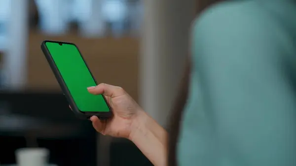 Unrecognizable executive typing green screen smartphone at lobby. Closeup woman hand touching empty mockup phone inside. Unknown ceo chatting online at chroma key display mobile during office break