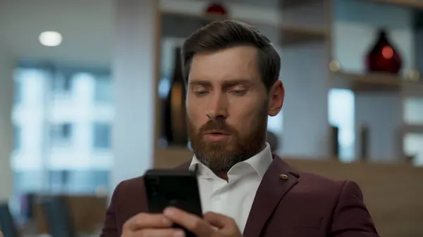 Annoyed boss reading email at job closeup. Stressed man disappointed bad work results looking mobile. Tired entrepreneur thinking watching smartphone. Focused manager solving problems at luxury office