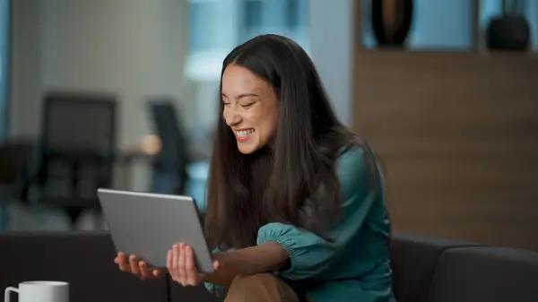 Laughing girl chatting computer taking break at lounge. Closeup happy chief using tablet at office. Cheerful ceo having good mood holding tab device. Natural beauty woman feeling overjoyed alone