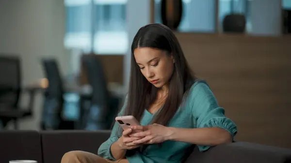 Calm woman scrolling feed resting at office closeup. Focused executive relaxing watching smartphone screen with attentive face. Successful director pondering having break. Corporate lifestyle concept