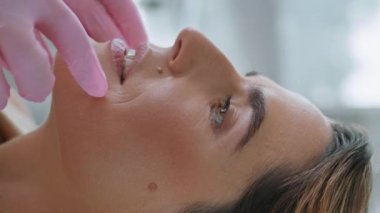 Prosedürü gençleştirmeden önce bilinmeyen bir kozmetik uzmanı tarafından muayene edilen kadın hasta dikey görüntüyü kapatıyor. Doktor dermatolog elleri kadının yüzüne dokunuyor. Deriyi inceliyor. Klinikte güzellik tedavisine hazırlanılıyor