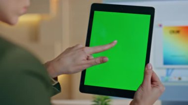 Bilinmeyen tasarımcı, iş yerindeki tablet tarama uygulamasına dokunuyor. Kadın elleri yeşil ekranlı bilgisayara dokunarak tasarımı seçiyor. Krom anahtar aygıtında mimar projesi oluşturan iş kadını