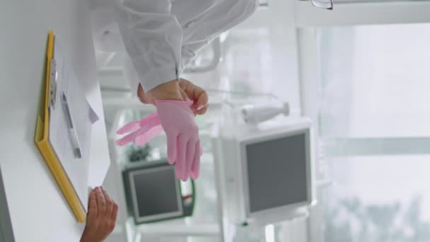 Опытная Женщина Косметолог Надевает Розовые Резиновые Стерильные Перчатки Руки Вертикально — стоковое видео