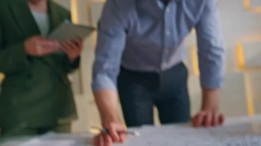 Ekip mühendisleri, yaratıcı mimari şirketinin planlarını inceliyor. Ciddi bir mimar kadın meslektaşına bina tasarısı gösteriyor. İki inşaat uzmanı mühendislik projesinde çalışıyor..